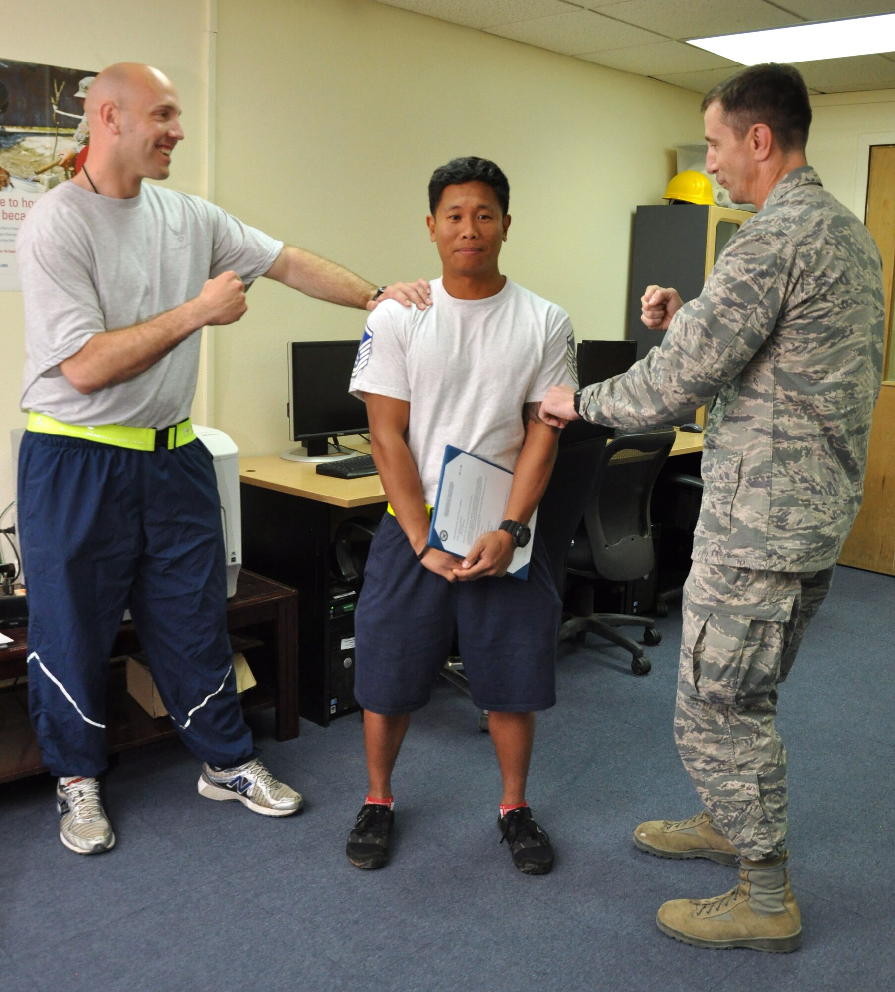 U.S. Air Force Brig. Gen. Kevin Schneider, right, 380th Air Expeditionary Wing commander, and U.S. Air Force Master Sgt. Christopher Waldrip, left, 380th Expeditionary Civil Engineer Squadron assistant chief of operations, prepare to "tack on" U.S. Air Force Master Sgt. Jason Ramirez's new senior NCO stripe Dec. 21, 2013, at a deployed location in Southwest Asia.  Ramirez, the 380th ECES assistant chief of training, received his promotion under the Air Force’s Stripes for Exceptional Performers program. Both Ramirez and Waldrip are deployed from RAF Mildenhall, England. (U.S. Air Force photo by Tech. Sgt. Colleen Urban/Released)