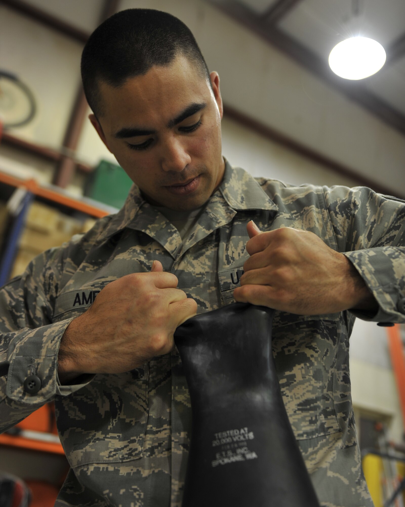 Staff Sgt. Joshua Amby performs a visual glove inspection at the 379th Air Expeditionary Wing, Southwest Asia, Dec. 30, 2013. Amby has tested 62 pairs of gloves since Dec. 23 which is a requirement for all gloves received and in current inventory. Gloves used daily are tested every six months or sooner if a glove is turned in for inspection. Amby is a 379th Expeditionary Civil Engineer Squadron electrical systems craftsman deployed from Ramstein Air Base, Germany and a Lanai City, Hawaii native. (U.S. Air Force photo by Master Sgt. David Miller)