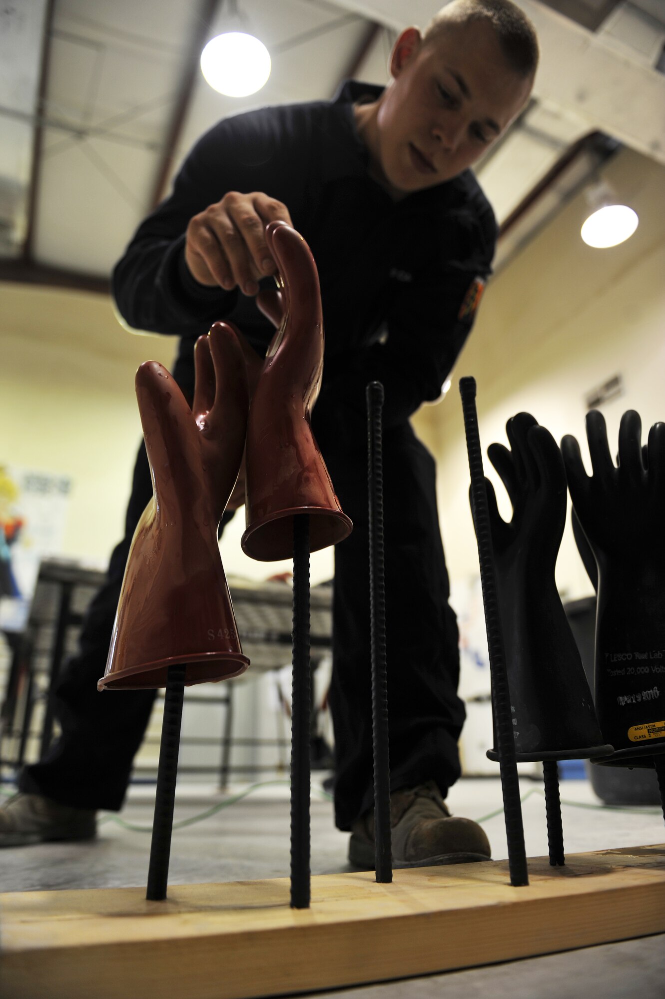 Senior Airman Justin Henke places a glove on a drying rod after testing at the 379th Air Expeditionary Wing, Southwest Asia, Dec. 30, 2013. Henke has tested 62 pairs of gloves since Dec. 23 which is a requirement for all gloves received and in current inventory. Gloves used daily are tested every six months or sooner if a glove is turned in for inspection. Henke is a 379th Expeditionary Civil Engineer Squadron electrical systems journeyman deployed from Ramstein Air Base, Germany and a Vicksburg, Miss., native. (U.S. Air Force photo by Master Sgt. David Miller)