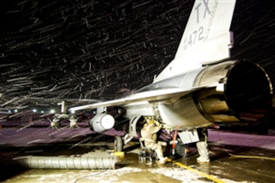A U.S. Air Force maintenance team works on an F-16 aircraft during a snow storm on Bagram Airfield in Parwan province, Afghanistan, Dec. 29, 2013. 