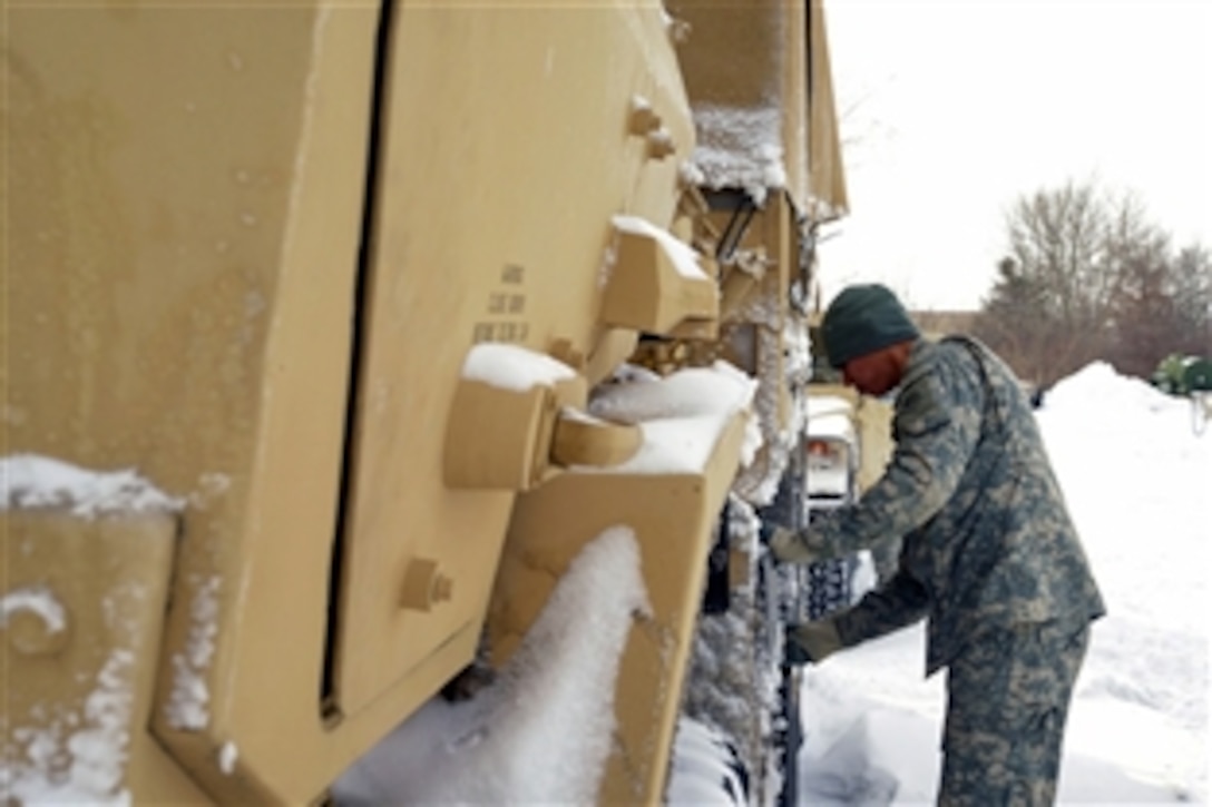 Spc. Eric Mendoza, a light wheeled vehicle mechanic from the 1166th Transportation Company of Worcester Mass., checks the battery on a military vehicle in Newburyport in preparation for winter storm response operations in Newburyport, Mass., Jan. 3, 2014.