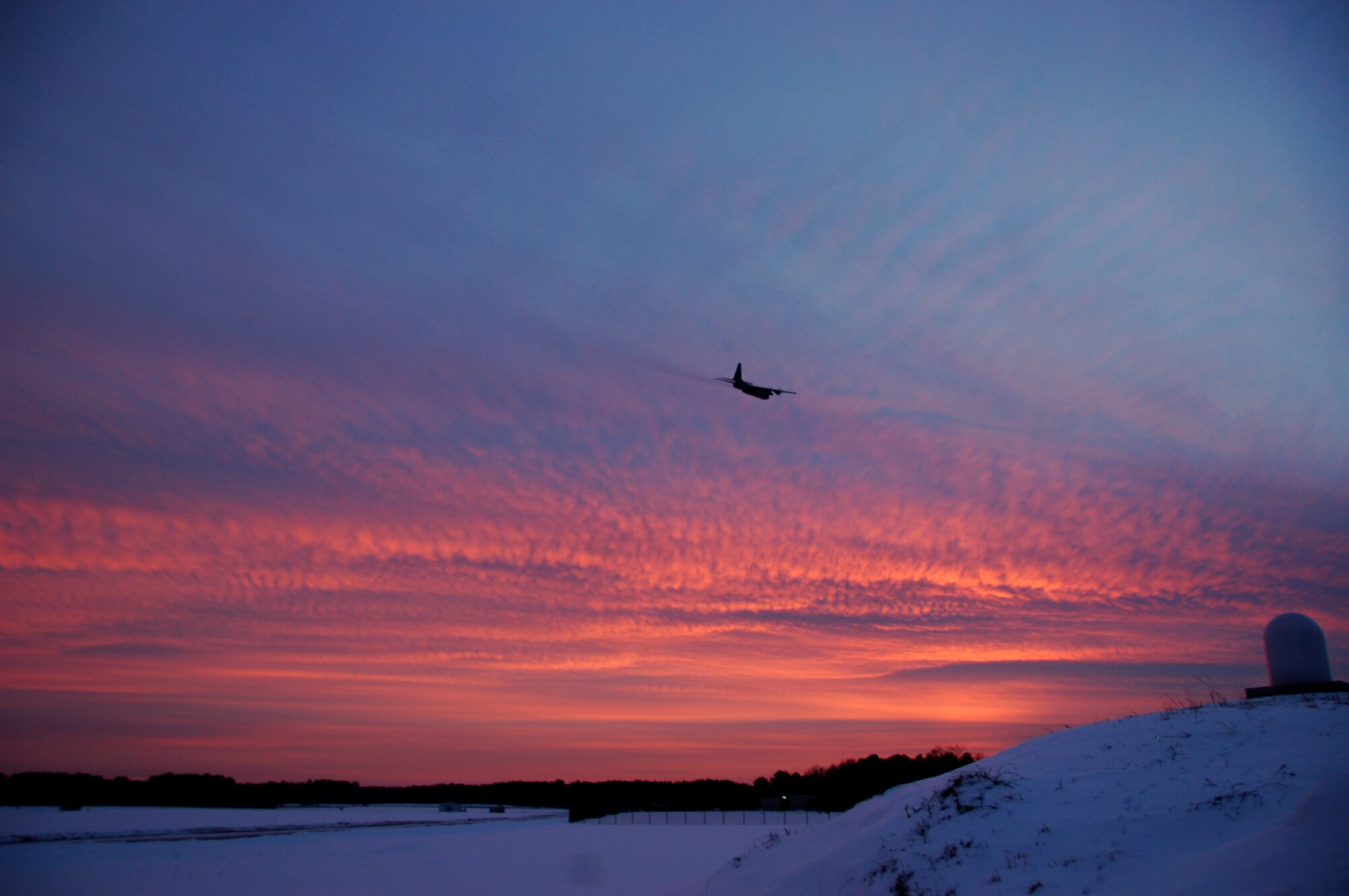 A C-130H Hercules aircraft assigned to the 103rd Airlift Wing flies off into the sunset at Bradley Air National Guard Base, East Granby, Conn., Dec. 19, 2013, marking the historic, first locally-generated sortie with the unit’s newly assigned airframe.  (U.S. Air National Guard photo by Maj. Bryon Turner)