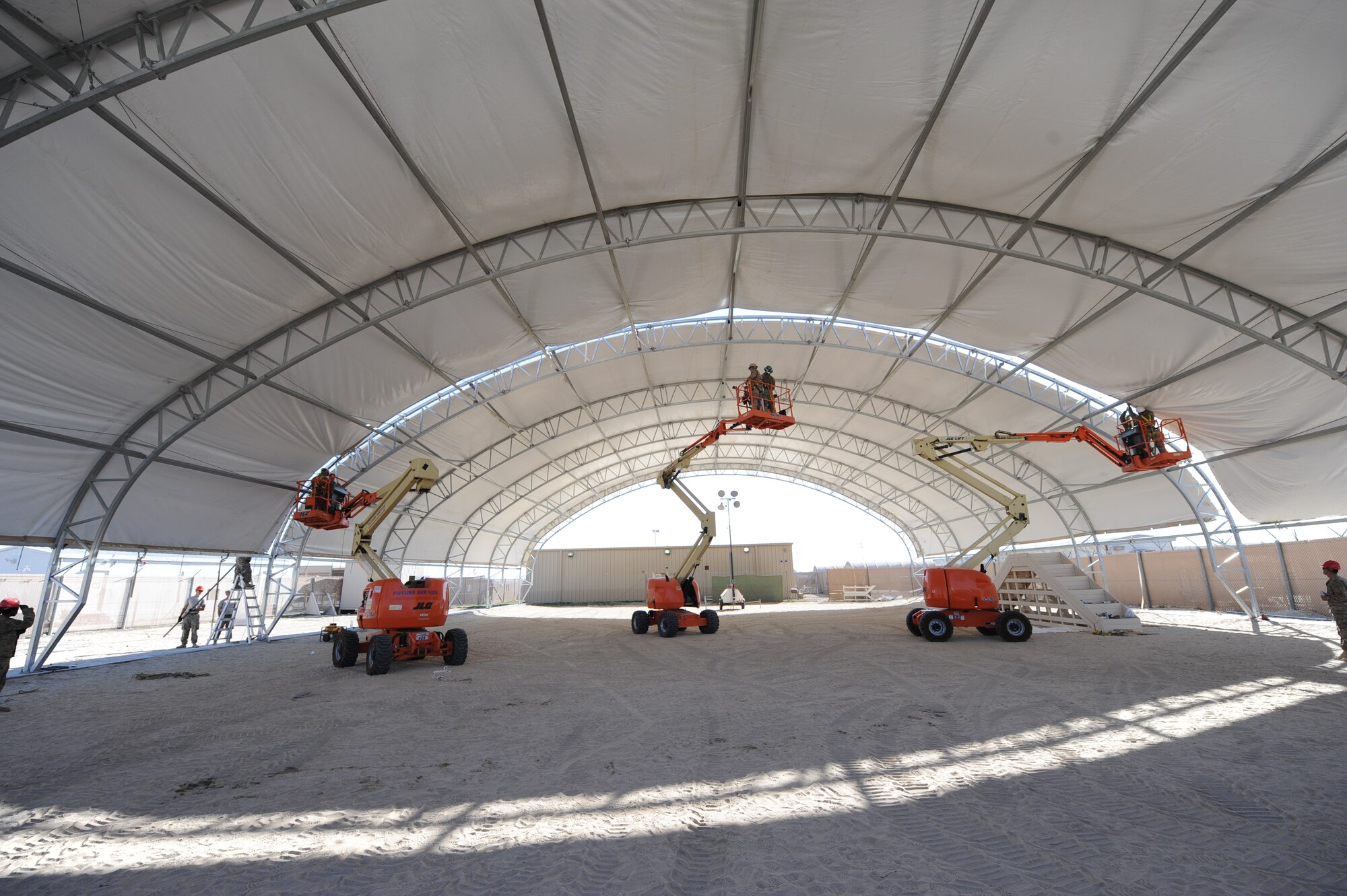 1st Expeditionary Civil Engineer Group J-2 team constructs a sun shade for the 386th Expeditionary Security Forces Squadron Military Working Dog section at an undisclosed location in Southwest Asia. Prior to installation, the K-9 teams performed repetitive training drills around base while dealing with inclement weather and temperatures that reached into the 100’s during the summer months. (U.S. Air Force photo by Senior Airman Desiree W. Moye)    
