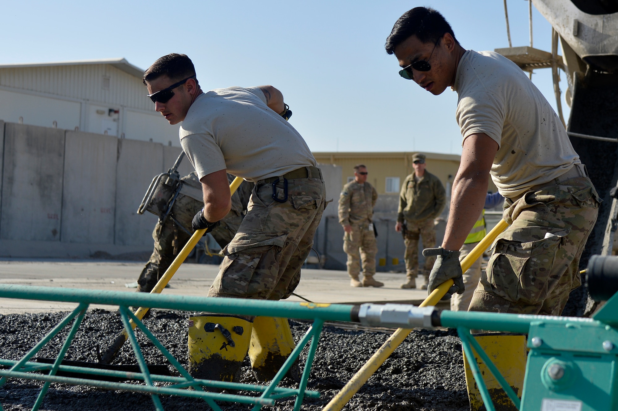 U.S. Air Force Senior Airman Dylan Sheets, 577th Expeditionary Prime BEEF Squadron heating, ventilation, and air conditioning specialist, and Senior Airman Mervin Santa Maria, 577th EPBS electrician, rake concrete at Kandahar Airfield, Afghanistan, Jan. 4, 2014. The 577th EPBS poured concrete for a large-area maintenance facility, which is about 8,000 square feet.  (U.S. Air Force photo by Senior Airman Kayla Newman/Released)