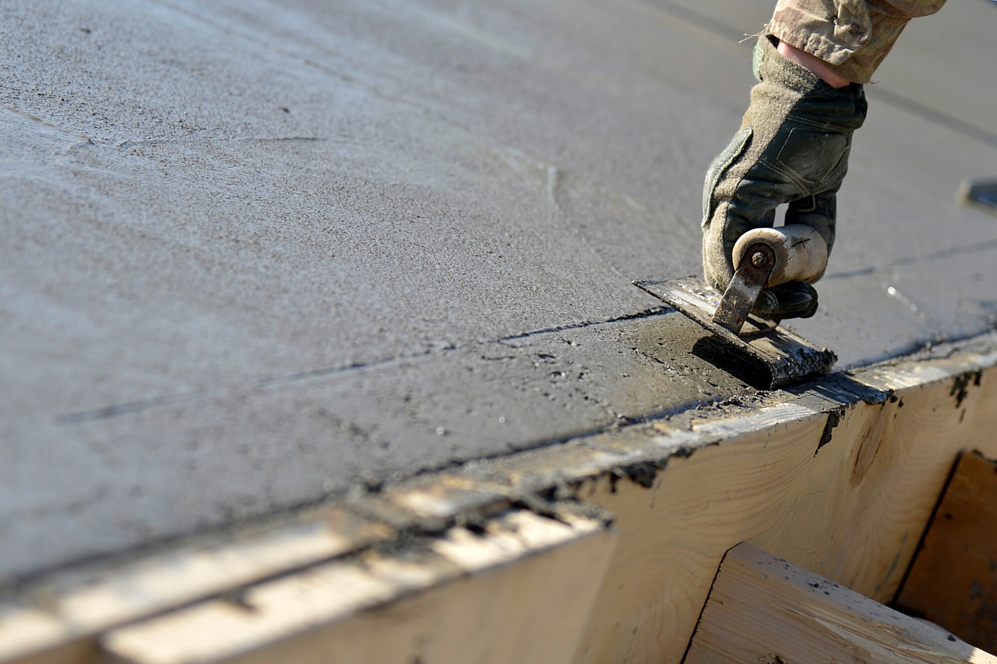 A U.S. Air Force Airman assigned to the 577th Expeditionary Prime BEEF Squadron smoothes concrete at Kandahar Airfield, Afghanistan, Jan. 4, 2014. The 577th EPBS poured concrete for a large-area maintenance facility, which is about 8,000 square feet.  (U.S. Air Force photo by Senior Airman Kayla Newman/Released)