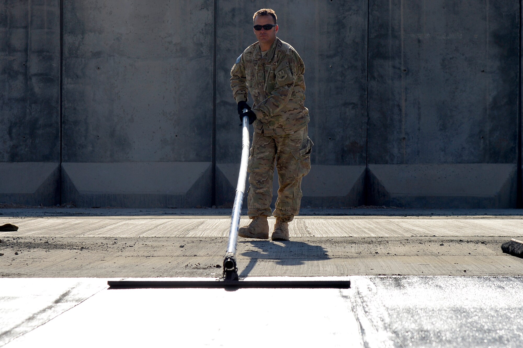 U.S. Air Force Staff Sgt. John Scherstuhl, 577th Expeditionary Prime BEEF Squadron pavements and equipment operator, smoothes concrete at Kandahar Airfield, Afghanistan, Jan. 4, 2014. The 577th EPBS poured concrete for a large-area maintenance facility, which is about 8,000 square feet.  (U.S. Air Force photo by Senior Airman Kayla Newman/Released)