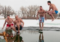One of 13 teams leaps into the icy waters of Sloan Lake, Cheyenne, Wyo., during the second annual Matthew S. Schwartz Memorial Polar Plunge Jan. 4, 2013. Participants braved 16-degree air and 30-degree water temperatures to raise money for a foundation established to help wounded explosive ordnance technicians and their families. The event is named for an F.E. Warren Air Force Base, Wyo., 90th Civil Engineer Squadron explosive ordnance technician who was killed in action while deployed to Afghanistan Jan. 5, 2012. (U.S. Air Force photo by R.J. Oriez)
