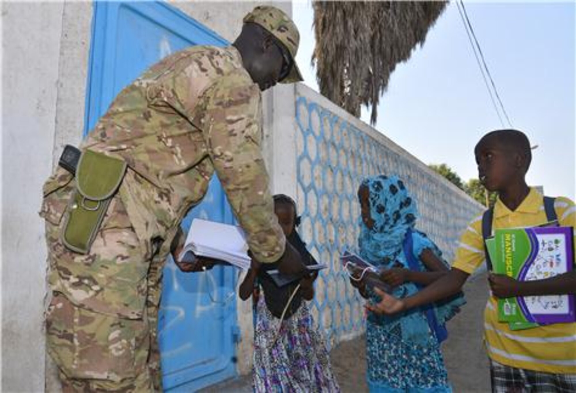U.S. Air Force Staff Sgt. Deng Pour, Combined Joint Task Force-Horn of Africa, noncommissioned officer in charge of religious affairs, gives school supplies to local children in Djibouti Dec. 15, 2013. Pour’s goal while in Africa is to give back to his peers and country. (U.S. photo by Staff Sgt. Antoinette Gibson/Released) 