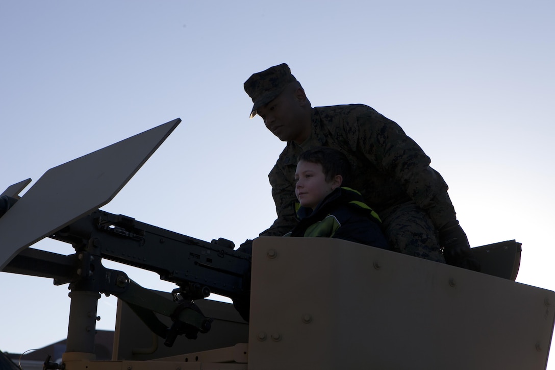Staff Sgt. Tarath Thlang, the communications chief for Headquarters Battalion, 14th Marine Regiment, helps a child into the turret of a military humvee at the Armed Forces Adventure Area in Fort Worth, Texas, Dec. 30, 2013. The AFAA was the official fan zone for spectators of the 2013 Bell Helicopter Armed Forces Bowl to interact with service members and their gear before, during and after the game.