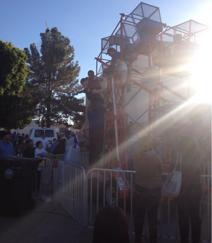 Sergeant Joshua Tyler Seabol, a Marine Aviation Logistics Squadron 13 aviation supply clerk and native of North Huntingdon, Pa., scales down a halted Ferris wheel and rescues an unidentified little girl at the 7th annual Somerton Tamale Festival at Somerton, Ariz., Dec. 21. (Courtesy photo by Sgt. Isamar Seabol)