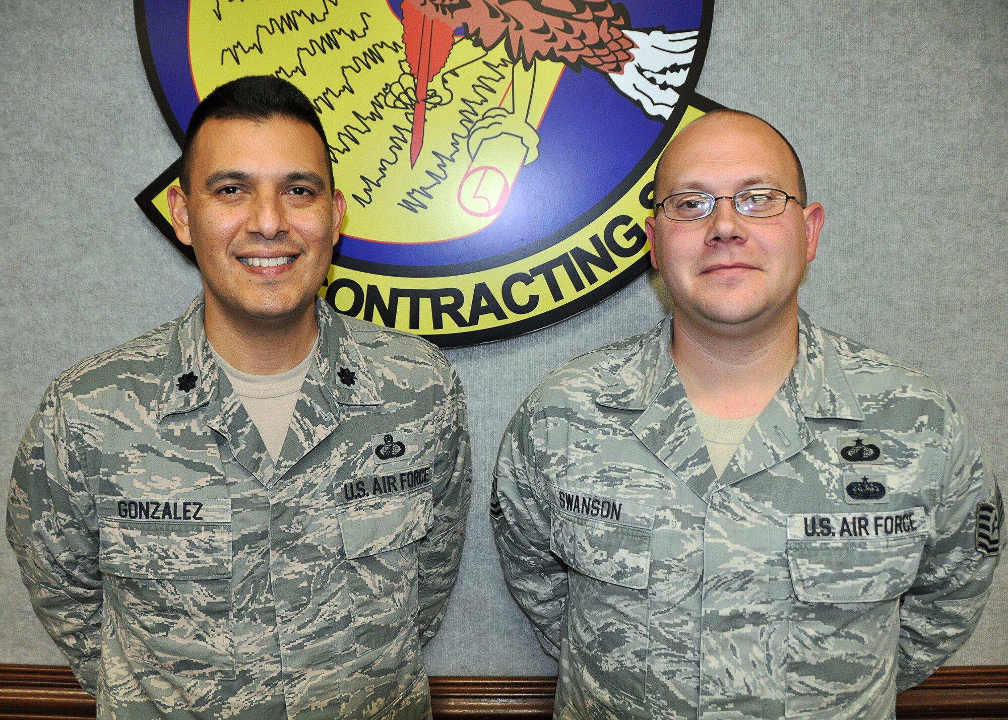 Lt. Col. Antonio J. Gonzales, 325th CONS commander, and Technical Sgt. Brian E. Swanson, 325th CONS Base Support Flight NCO in charge, pose for a photo in front of the 325th CONS shield. Air Combat Command selected both Airmen for contracting awards. (U.S. Air Force photo by Staff Sgt. Rachelle Blake)