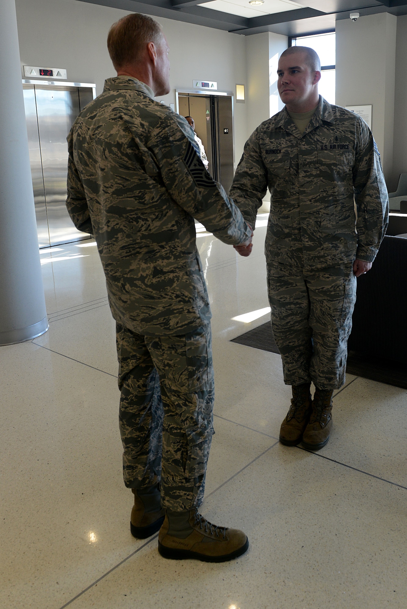 From left, Chief Master Sgt. of the Air Force James A. Cody presents Staff Sgt. Jeremy Burnock, 633rd Medical Support Squadron histopathology technician, with one of his challenge coins during a visit to Langley Air Force Base, Va., Jan. 7, 2014. Cody visited multiple wings and discussed force management issues, budget concerns and the future of the enlisted force with Airmen. Burnock is originally from Detroit. (U.S. Air Force photo by Airman 1st Class Kimberly Nagle/Released)