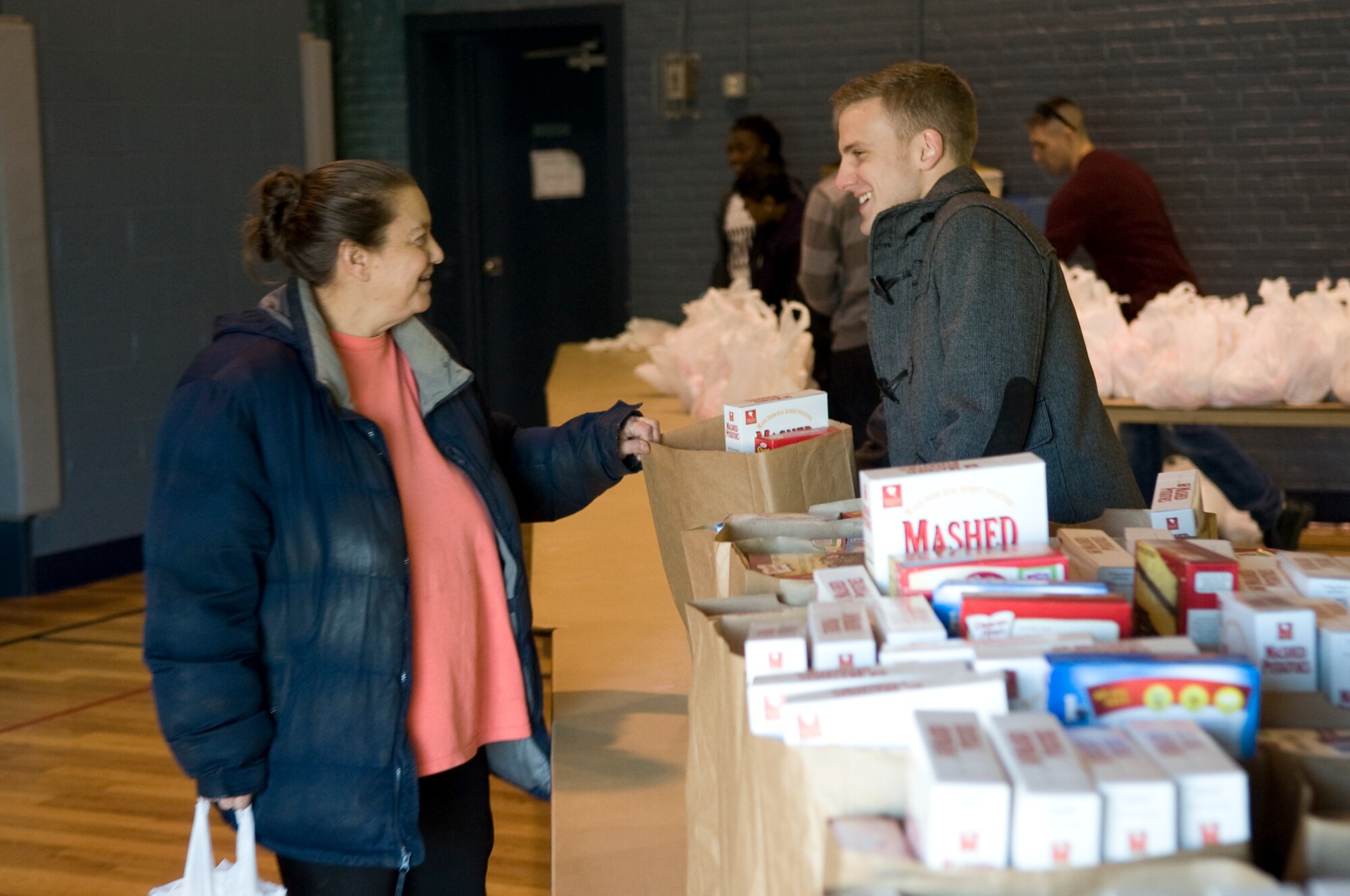 Susan Tatmen, a mother of three children, talks with Airman Christian Terrell, 436th Aerial Port Squadron ramp service specialist, while receiving her food basket, Dec. 13, 2013, at the Salvation Army in Dover, Del. Terrell was part of a team of Airmen that helped the Salvation Army organize and pass out food baskets. (U.S. Air Force photo/Senior Airman Jared Duhon)