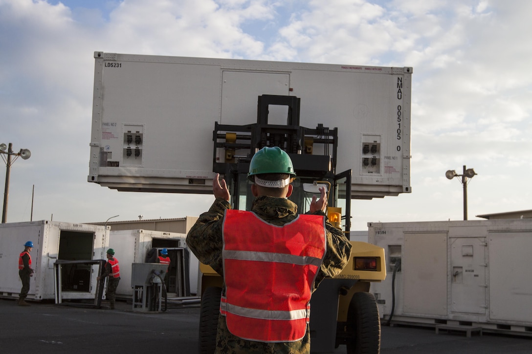 Cpl. Aaron Barbosa, a mobile facilities technician with Marine Aviation Logistics Squadron 12, directs a forklift that is lifting a mobile facility, Jan. 6, 2014. The move comes as part of the construction work provided by the Defense Policy Review Initiative.