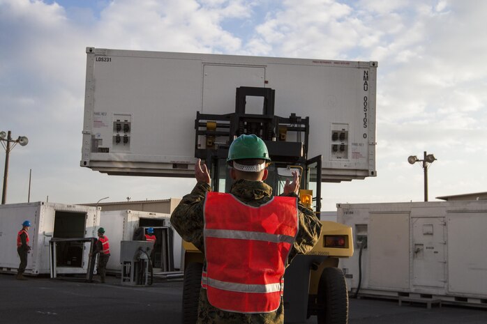 Cpl. Aaron Barbosa, a mobile facilities technician with Marine Aviation Logistics Squadron 12, directs a forklift that is lifting a mobile facility, Jan. 6, 2014. The move comes as part of the construction work provided by the Defense Policy Review Initiative.