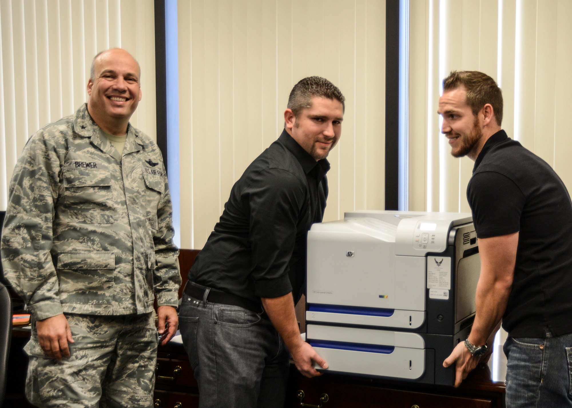 Russell Bomar (right), 412th Communications Squadron, Print Services technician and Andrew King (center), 412th CS Print Services lead, start the printer "right sizing" initiative by collecting 412th Test Wing Commander Brig. Gen. Michael Brewer's office printer. The Project84 idea was implemented on Edwards as a way to save costs on printer ink, toner, paper and maintenance. Excess printers will be collected from buildings and there will be an increase in sharing printers. (U.S. Air Force photo by Rebecca Amber) 
