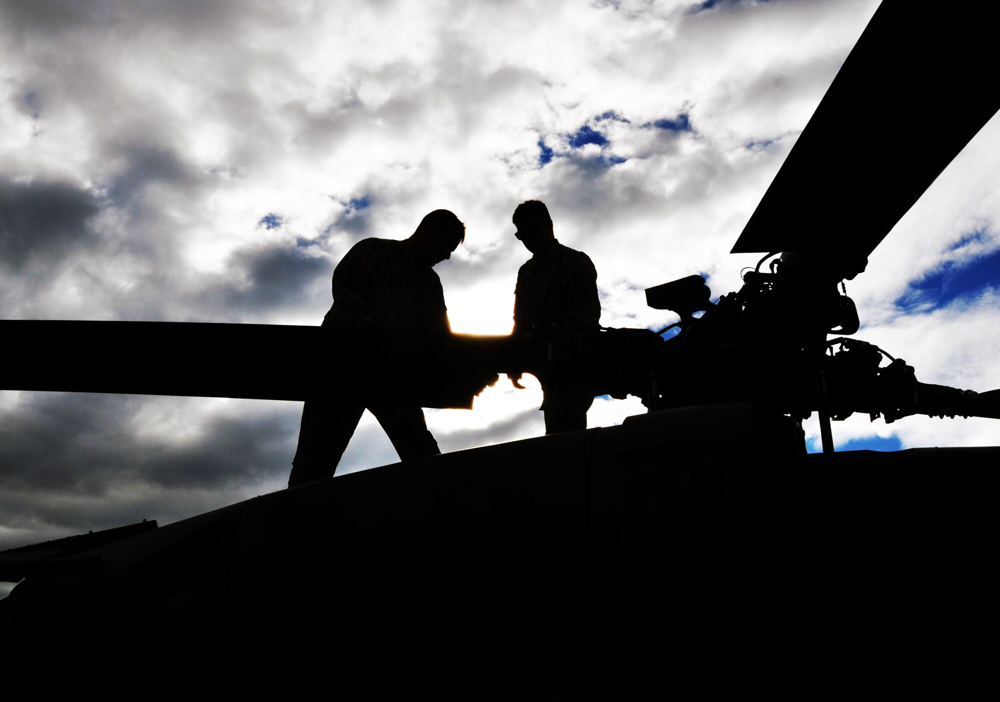 Two crew chiefs assigned to Joint Task Force-Bravo’s 1-228th Aviation Regiment perform maintenance on the main rotor of a UH-60 Blackhawk helicopter as the sun sets on the flightline at Soto Cano Air Base, Honduras, Jan. 8, 2014.  Crew chiefs work constantly to ensure JTF-Bravo aircraft are mission ready at all times.  (U.S. Air Force photo by Capt. Zach Anderson)