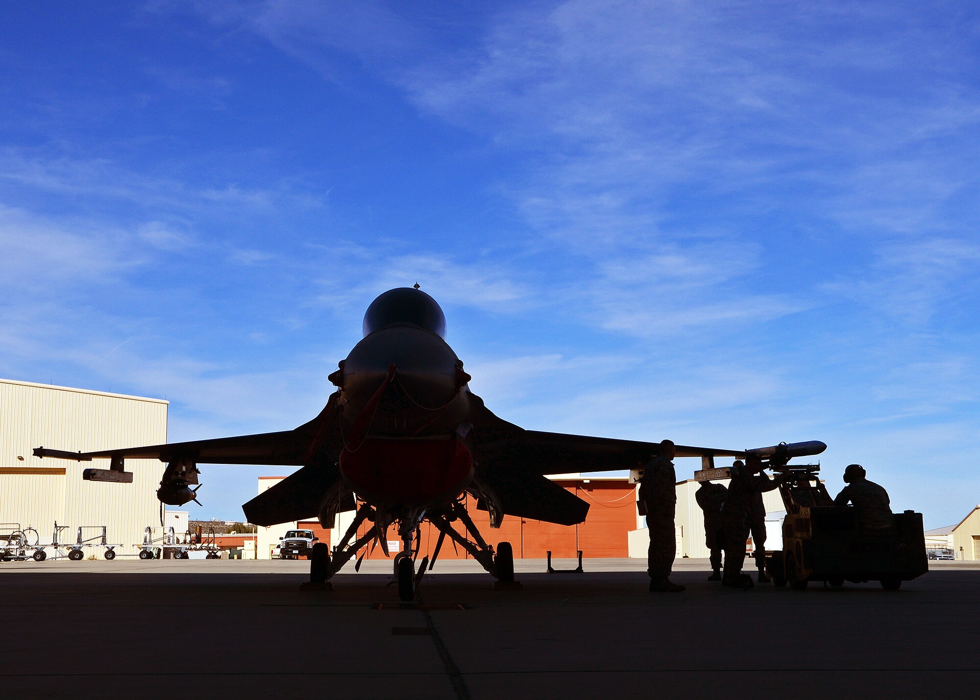 Weapons load crew members with the 445th Aircraft Maintenance Unit work to load an F-16 Falcon against the Edwards flightline backdrop during the Fourth Quarter Fighter Weapons Load Competition Jan. 6, 2014. Weapons load crew members from the 445th, 411th FLTS and 461st AMU competed in the friendly competition to showcase each crew member’s talent. the 445th AMU claimed the title for this quarter.(U.S. Air Force photo by Jet Fabara)