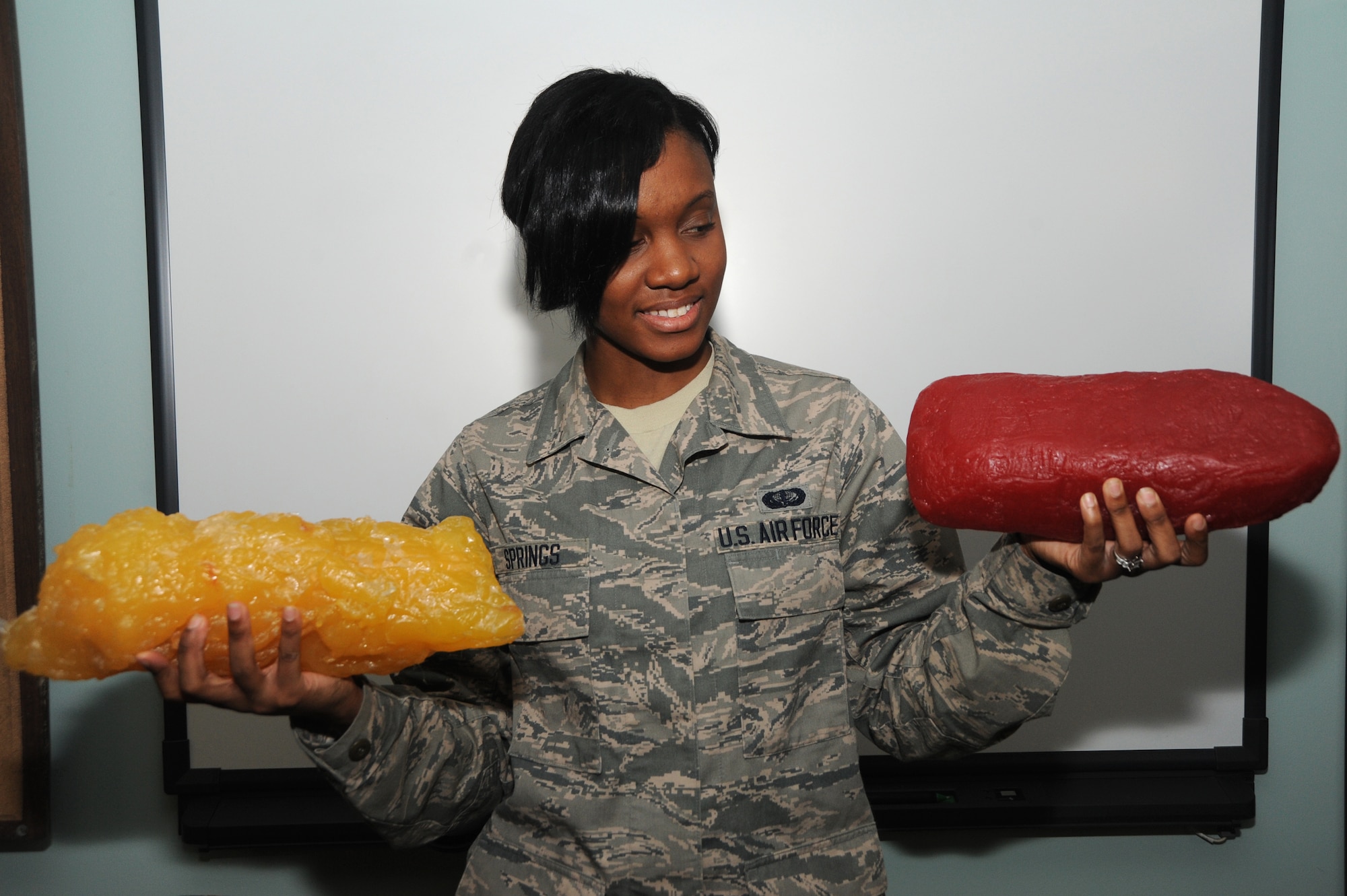 Airman 1st Class Tkeyah Springs, 375th Force Support Squadron fitness specialist, observes replicas of five pounds of fat and five pounds of muscle. Many people are aiming to lose fat and gain muscle for New Year’s resolutions. (U.S. Air Force photo/Airman 1st Class Megan Friedl)