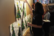 Minot State University Senior Stephanie Hancock, along with other members of MSU’s Entrepreneur Club, hang art work from kindergarten students at North Plains Elementary School, located on Minot Air Force Base, in the Beaver Brew Café in downtown Minot Dec. 19, 2013. Hancock hopes to not only create a stronger bond between the base and city communities, but to promote and inspire students by displaying their art work. (U.S. Air Force photo/Airman 1st Class Lauren Pitts)