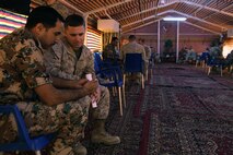 1st Lt. Tyler A. Reed, a Santa Monica, Calif., native, and the communication plans officer with U.S. Marine Corps Forces Central Command (Forward), looks at Maj. Jumah Mfleh Hajij’s, the communication plans officer with Communications Group, Royal Jordanian Armed Forces, phone while he shows pictures of his family during the first day of Exercise Eager Lion 2013 at Camp Titin, Jordan, June 9, 2013.