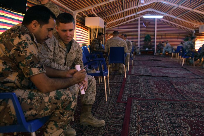 1st Lt. Tyler A. Reed, a Santa Monica, Calif., native, and the communication plans officer with U.S. Marine Corps Forces Central Command (Forward), looks at Maj. Jumah Mfleh Hajij’s, the communication plans officer with Communications Group, Royal Jordanian Armed Forces, phone while he shows pictures of his family during the first day of Exercise Eager Lion 2013 at Camp Titin, Jordan, June 9, 2013.