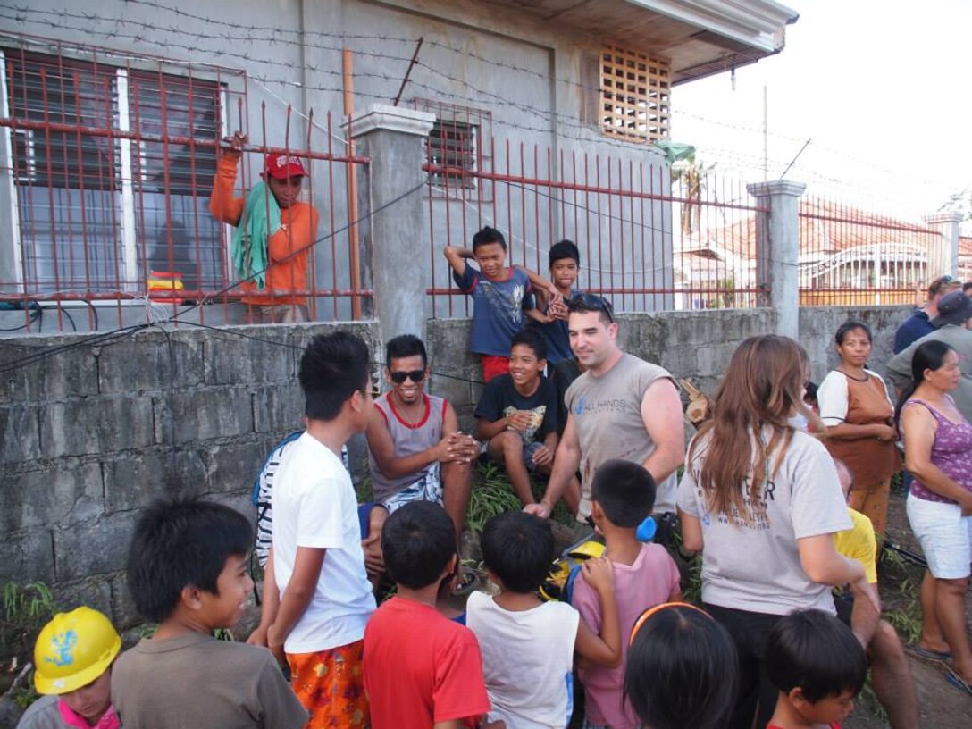 Capt. Neil Bucken, supply officer for 12th Marine Corps District talks with children during his volunteer trip with All Hands Volunteers Organization to the Philippines for 12 days to help with the relief efforts after the earthquake and Super Typhoon Haiyan in late 2013. 