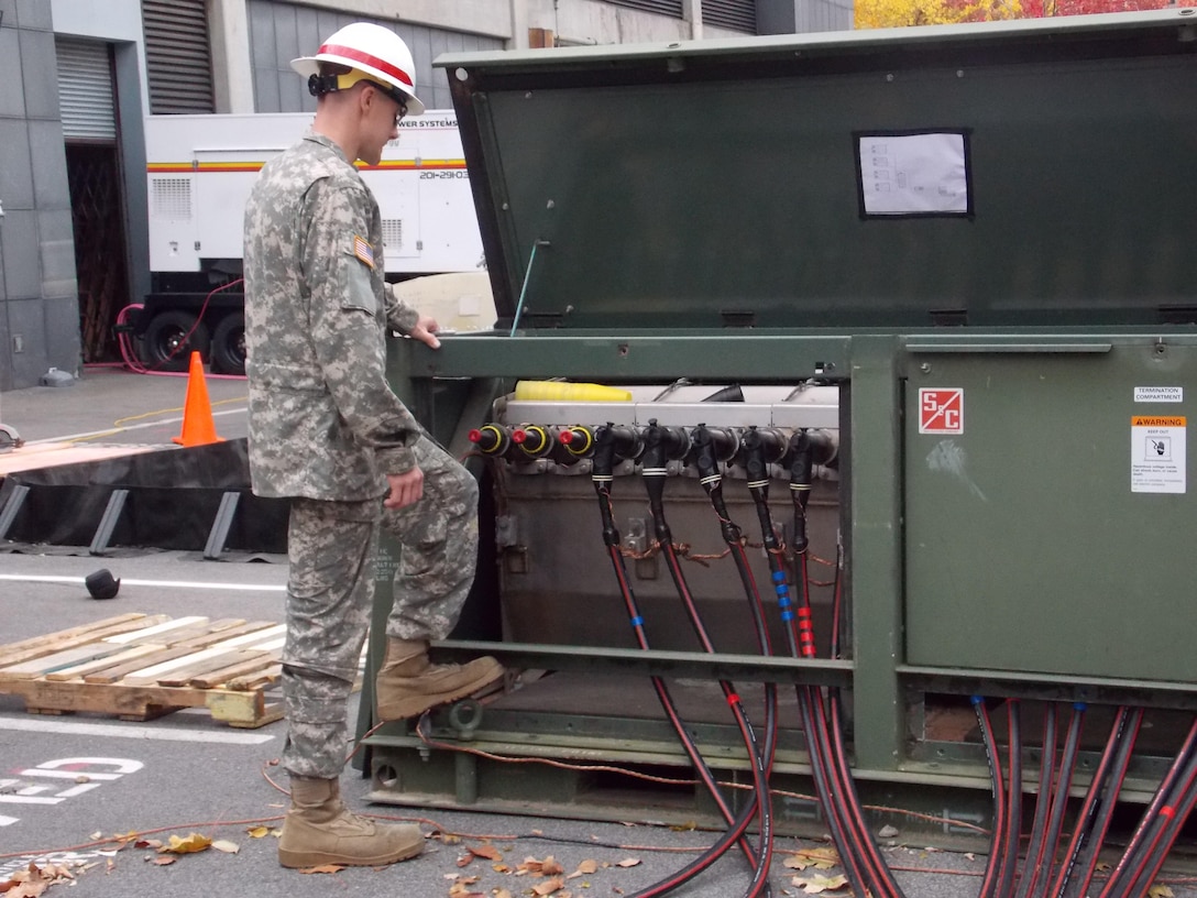 A member of the 249th Engineer Battalion inspecting the Primary Switching Center’s generator connections and grounds. 