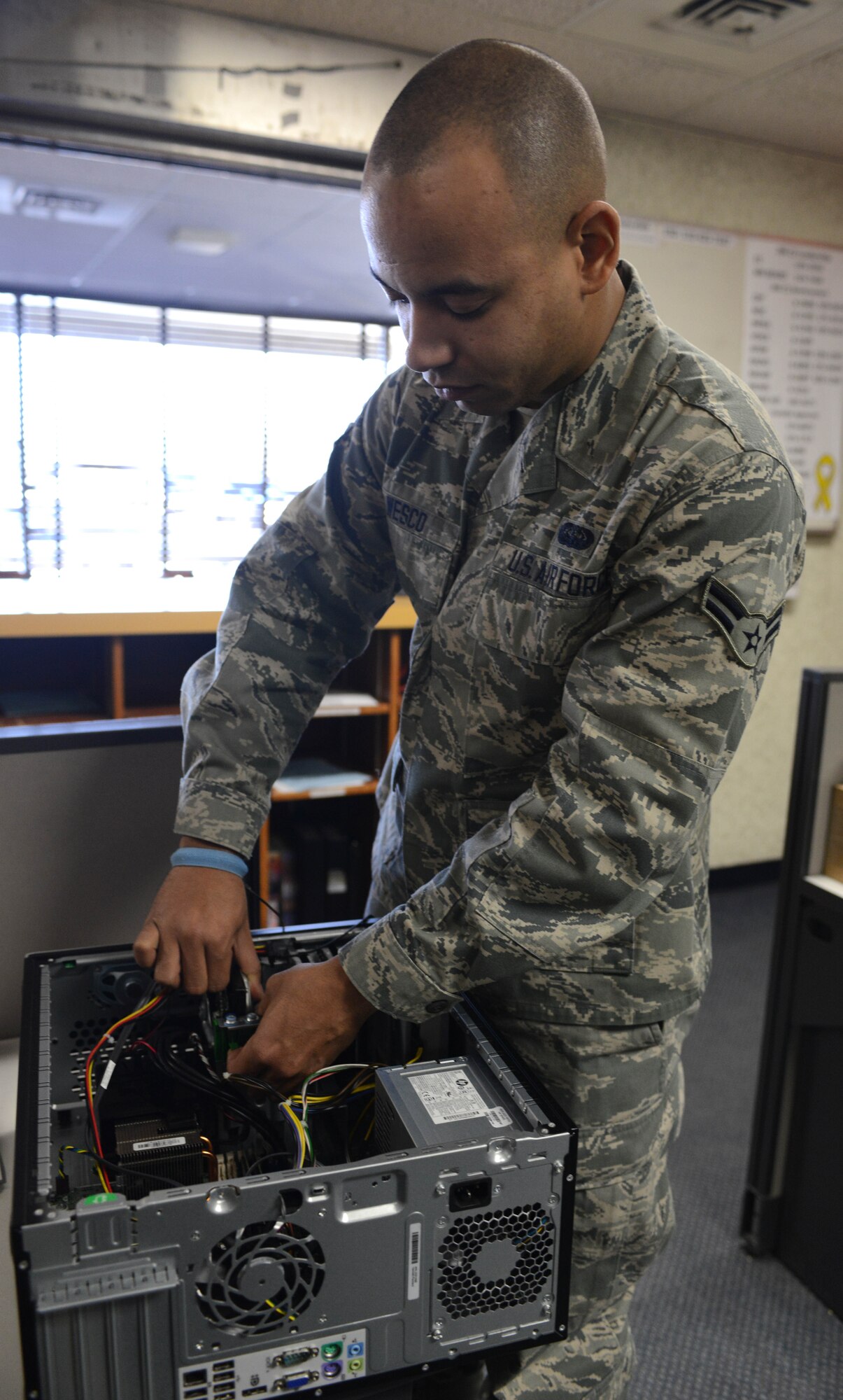 U.S. Air Force Airman 1st Class Lamar Wesco, 366th Communications Squadron client systems technician, repairs a computer tower, Jan. 9, 2014, at Mountain Home Air Force Base, Idaho. Picking up as much as 40 percent of local calls made to the ESD, the new satellite site process expedites ticket submissions for resolving computer issues. (U.S. Air Force photo by Senior Airman Caitlin Guinazu/Released)