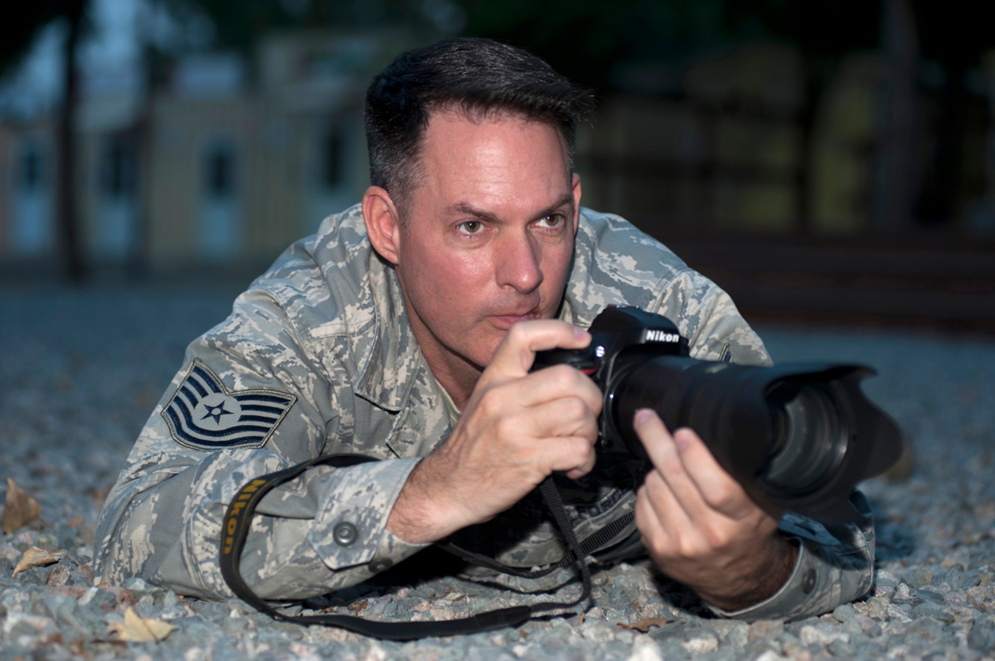 Tech. Sgt. Robert Gibson prepares to take photos from a low angle at Transit Center at Manas, Kyrgyzstan, August 8, 2013. Gibson, deployed out of Homestead Air Reserve Base, Fla., has always had a passion for photography. He used to be a combat photographer in the Army but separated in 1992 to spend a couple of years in college, and then joined the Air Force Reserve in 1994 for his current occupation. His hometown is Woodville, Texas. (U.S. Air Force photo/Staff Sgt. Robert Barnett)