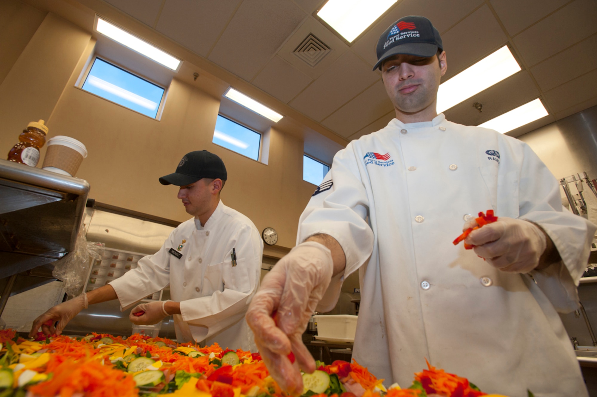Senior Airman Michael Ramos, right, and Spc. Christopher Muñoz prepare salads in the Iditarod dining facility kitchen at Joint Base Elmendorf-Richardson Tuesday. Munoz is participating in a cook exchange program in which Soldiers and Airmen take turns serving at the opposite branch’s DFACs. Muñoz is a food operations specialist for the 545th Military Police Company, and a native of Las Vegas, Nev. Ramos is the Iditarod morning shift leader for the 673d Force Support Squadron, and a native of Middletown, N.Y. (U.S. Air Force photo/Staff Sgt. Robert Barnett) 
