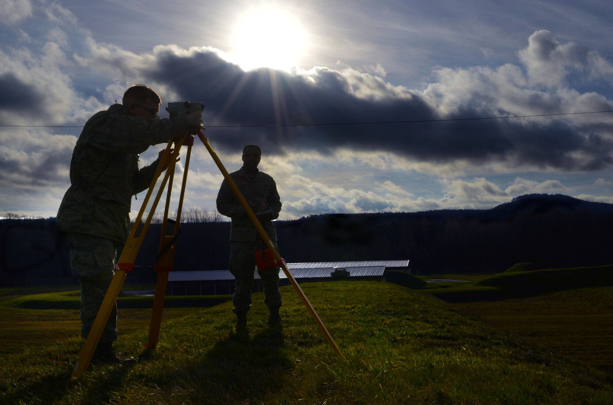 Airman 1st Class Justin Mason, 86th Civil Engineering Squadron engineering assistant and Senior Airman Dwayne Stewart 86th CES geobase technician, uses a total station measuring tool to measure the level of protective soil on munition depots, Jan. 8, 2014, Ramstein Air Base, Germany. The 86th CES uses geographic information systems to map the entire KMC area for the contractors who create blueprints for base development. (U.S. Air Force photo/Airman Dymekre Allen)