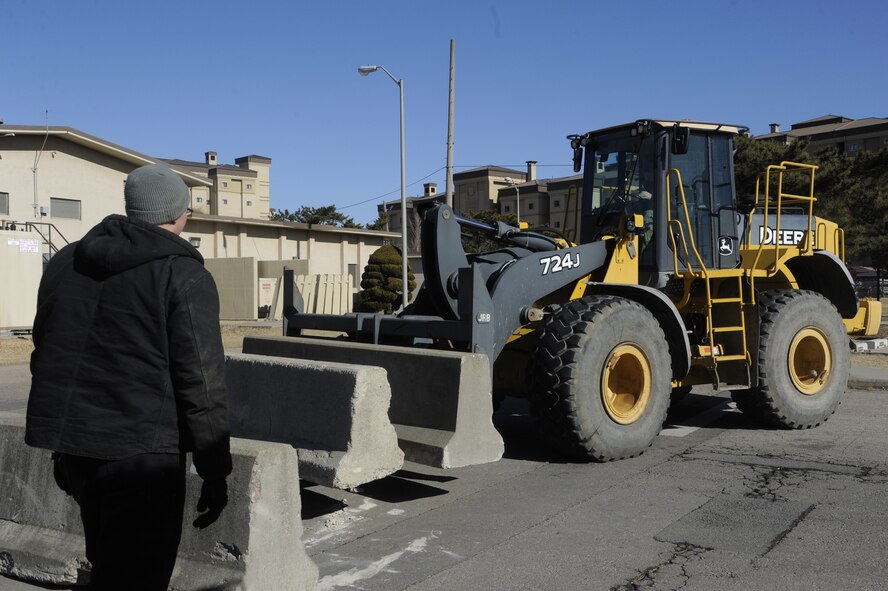 Airman 1st Class Jerry Franklin, 8th Civil Engineer Squadron journeyman, and Staff Sgt. Collin Tompkins, 8th CES craftsman, work together to place barriers around designated buildings on Kunsan Air Base, Republic of Korea, Jan. 9, 2014. The placement of barriers was part of Beverly Sentinel 14-1, a barrier exercise that tested the base’s ability to implement higher security measures at a moment’s notice.  (U.S. Air Force photo by Staff Sgt. Jessica Haas/Released) 