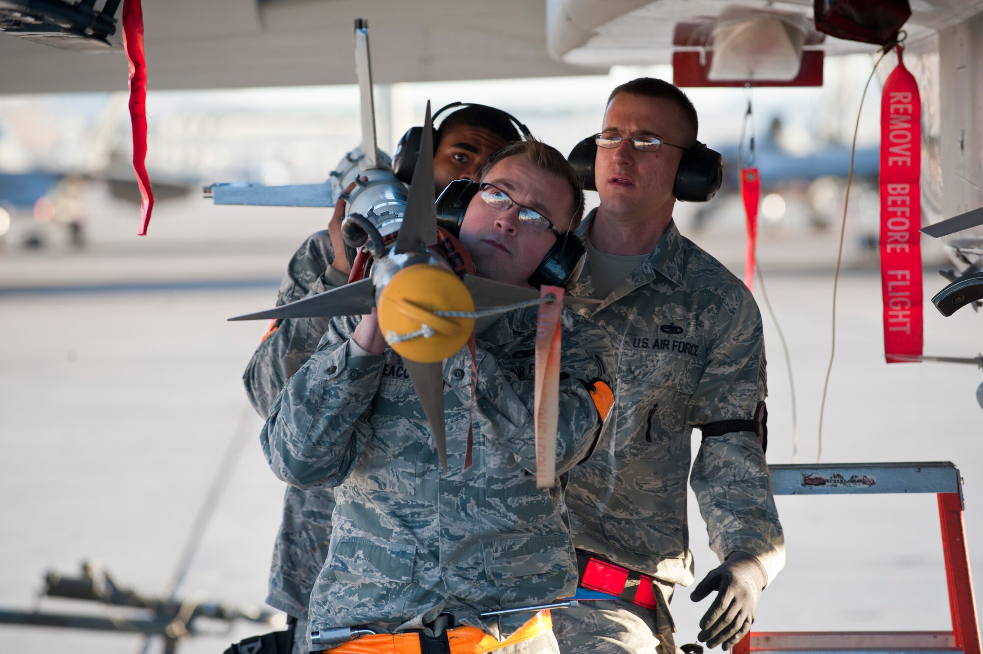 Airman 1st Class Jonathan Deacon (front) and Airman 1st Class Marcus Pinkney (back), 757th Aircraft Maintenance Squadron weapons load crew members, and Staff Sgt. Ronald Jefcik (middle), 757th AMXS weapons load crew chief, prepare to load an inert AIM-9 sidewinder missile during a quarterly load crew competition, Jan. 10, 2014, at Nellis Air Force Base, Nev. Weapons load crew competitions are held quarterly for Airmen to hone and maintain their skills while also recognizing superior performance. (U.S. Air Force photo by Airman 1st Class Thomas Spangler)