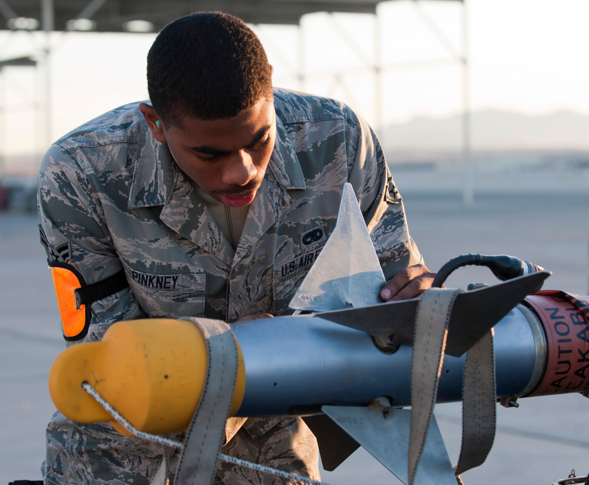 Airman 1st Class Marcus Pinkney, 757th Aircraft Maintenance Squadron weapons load crew member, prepares to load an inert AIM-9 sidewinder missile during a quarterly load crew competition, Jan. 10, 2014, at Nellis Air Force Base, Nev. The 757th AMXS load crews were competing to see which crew could correctly load weapons on to their respective aircraft the quickest. (U.S. Air Force photo by Airman 1st Class Thomas Spangler)