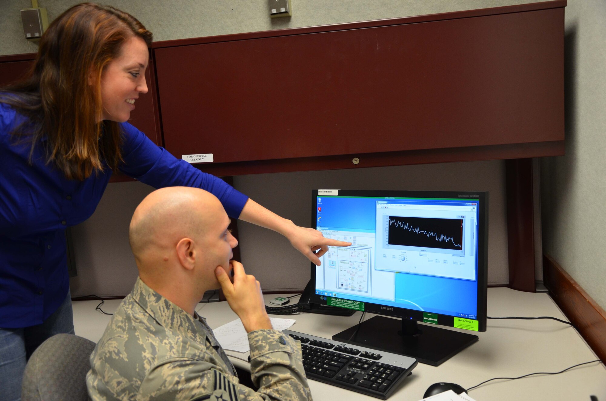 Dr. Theresa Hofstetter, a mass spectrometry scientist and Tech. Sgt. Daniel McAllister, an exercise and evaluations noncommissioned officer in charge, both with the Air Force Technical Applications Center at Patrick AFB, Fla., review coded algorithms at one of two stand-alone computer terminals that are capable of simulating AFTAC's custom thermal ionization mass spectrometers, or TIMS.  The duo is part of AFTAC's Innovation Lab, a concept dedicated to developing technologies at a lower cost to reduce operations maintenance and overhead. (U.S. Air Force photo by Susan A. Romano)