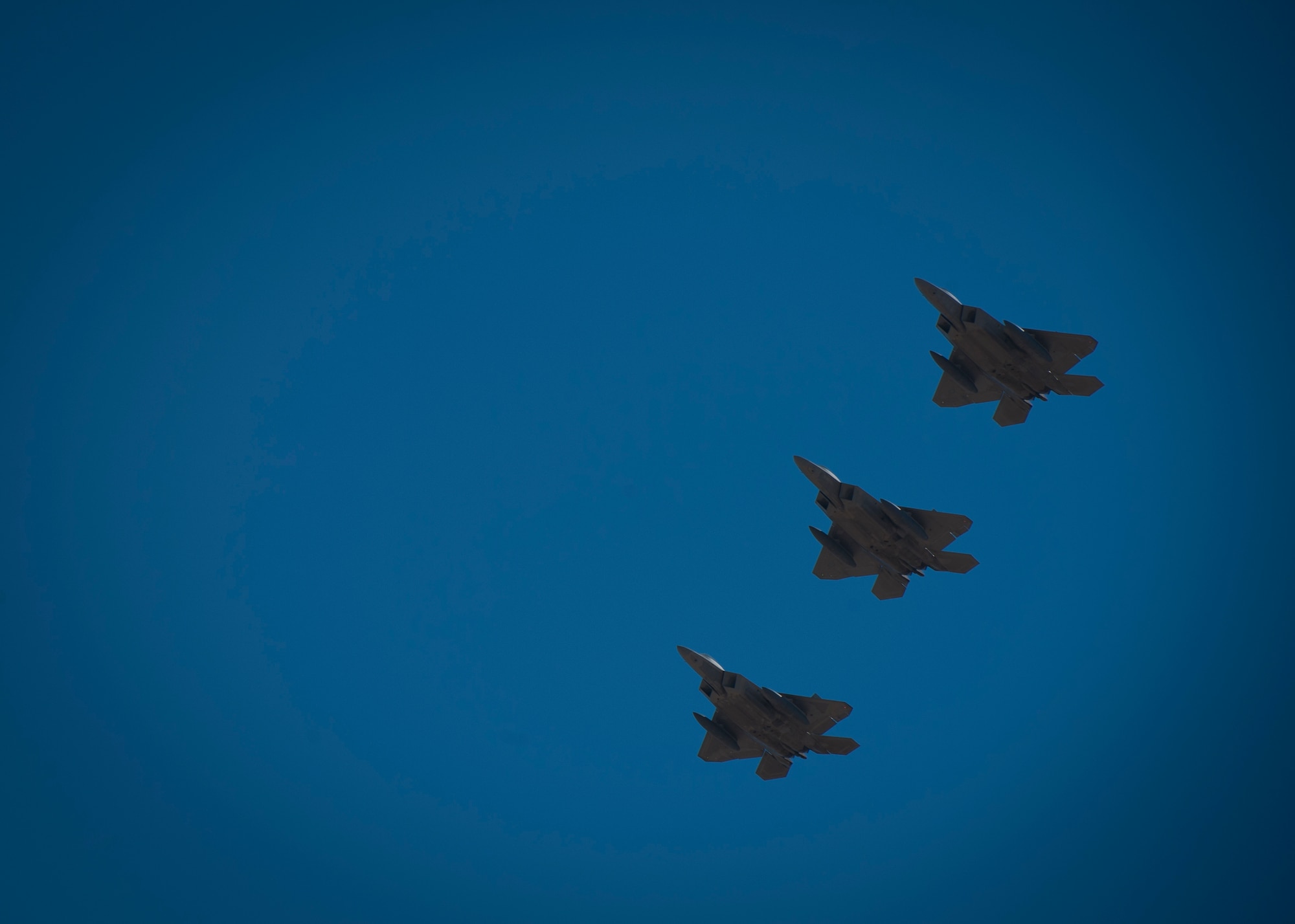 Three F-22 Raptors fly in formation over the base during their departure from Holloman Air Force Base, N.M., Jan. 6. The first five of 24 combat-deployable F-22 Raptors left Holloman heading to Tyndall Air Force Base, Fla. as a permanent change of station. The five F-22s that left Jan. 6 will be followed by six Raptors leaving each month until the move is completed. (U.S. Air Force photo by Airman 1st Class Aaron Montoya)