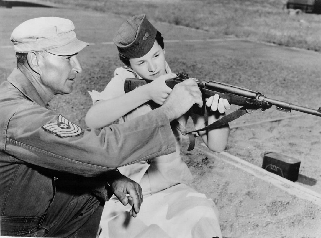 GURTIE GRABS A GUN. Cadet Roberta Wood, regional selectee to the International Exchange at Hawaii, receives instructions on firing an M-1 at Malmstrom AFB. Cadet Wood was attending her third encampment as a Civil Air Patrol member in Montana. (Strategic Air Command Archives)
