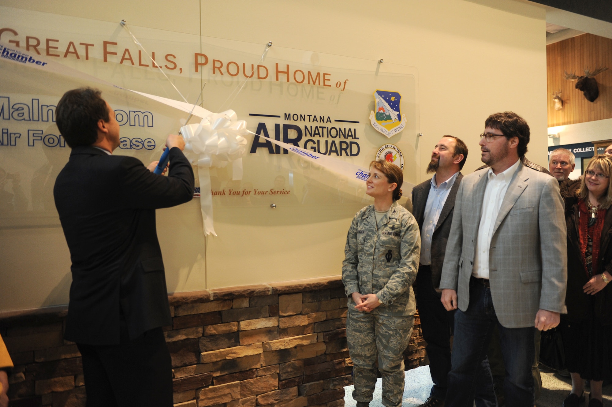 Steve Bullock, Montana governor (left), cuts a ribbon after a sign representing Malmstrom Air Force Base and Montana Air National Guard was mounted at the Great Falls International Airport in Great Falls, Mont., on Jan. 8. The sign was donated by the Montana Defense Alliance and the Military Affairs Committee of the Great Falls Area Chamber of Commerce. (U.S. Air Force photo/Senior Airman Katrina Heikkinen)