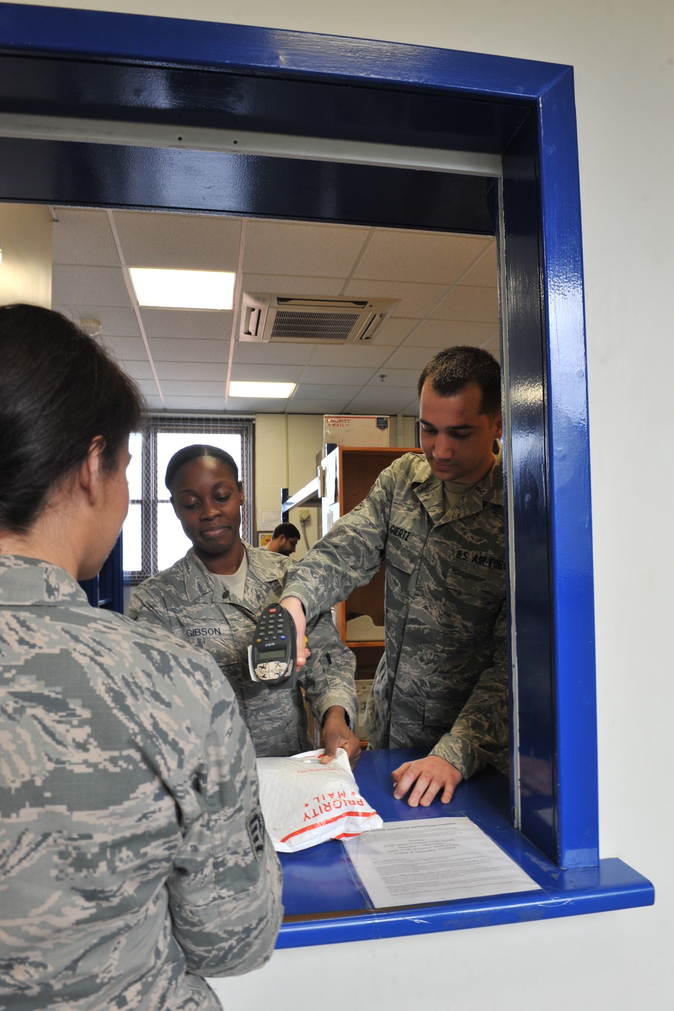 U.S. Air Force Staff Sgt. Keundra Gibson, 65th Communications Squadron custodian of postal effects, and Senior Airman Charles Giertz, 65th CS postal clerk, assist a customer picking up a package at the Lajes Field Post Office Jan. 9, 2014. The 65th CS Postal Service team was recently awarded the Information Dominance Air Force Outstanding Small Postal Facility Award for 2013. (U.S. Air Force photo by Staff Sgt. Angelique N. Smythe)