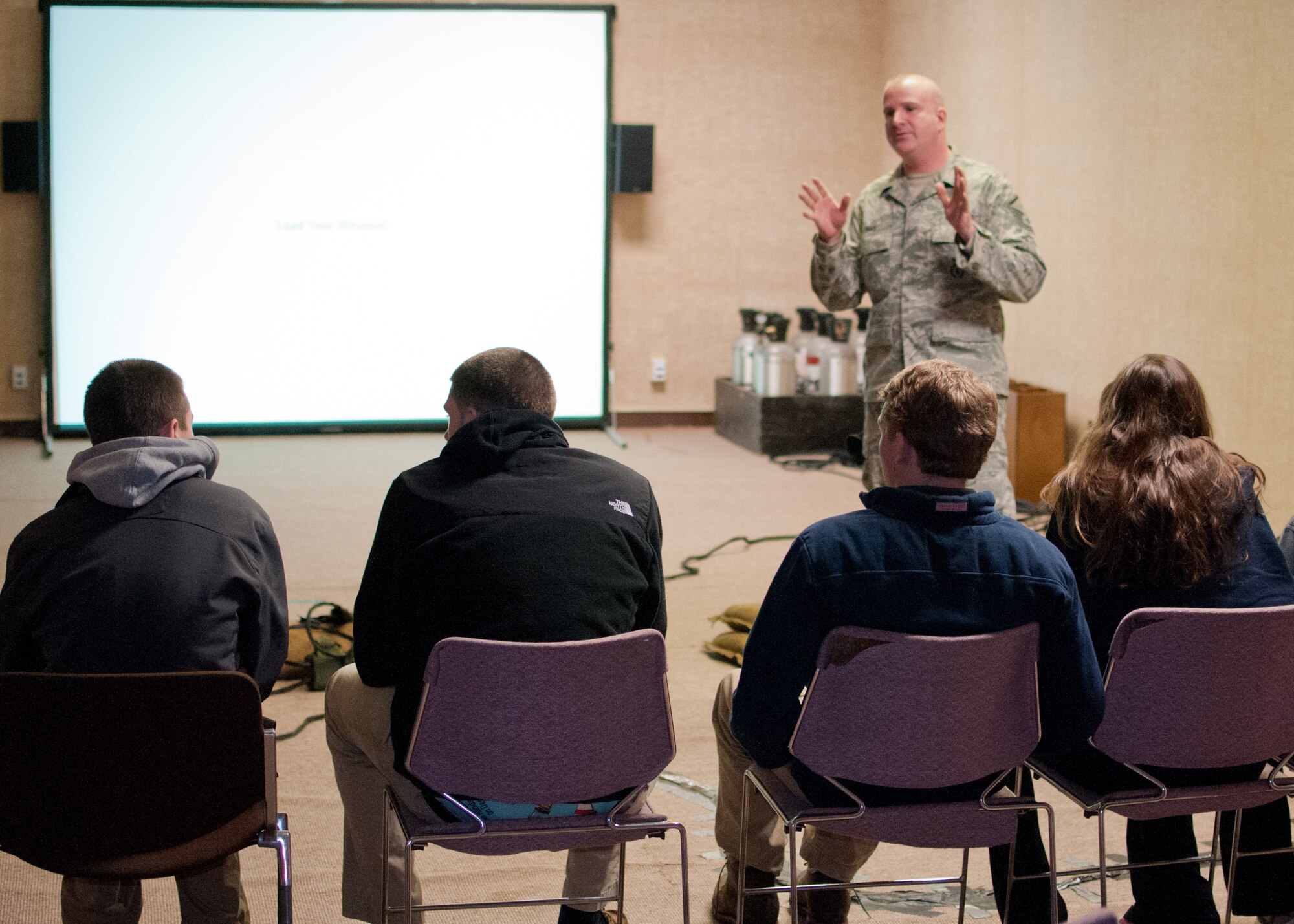 Master Sgt. Sean Dias, of the 102nd Security Forces Squadron talks with students from Sandwich Highschool on use-of-force techniques, laws, and concepts on Otis Air National Guard base, December 12, 2013. The students training was part of a law enforcement class and included the use of situation simulator which trains people how to react when faced with different law enforcement scenarios. (National Guard photo by Master Sgt. Aaron Smith/Released)