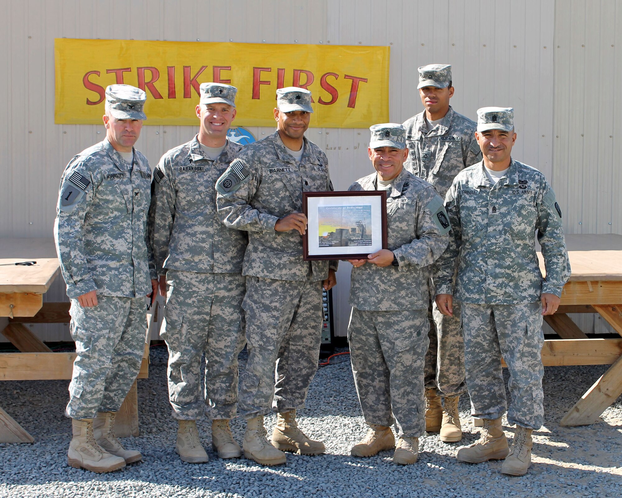 The command team from the 31st Air Defense Artillery Brigade and the 1st Bn. 44th ADA Regiment along with the unit ministry team, poses with the dedication plaque for the ribbon cutting ceremony for the grand opening of the Command Sergeant Maj. James D. Blankenbecler Resiliency Center, Dec. 21, 2013. The Resiliency Center is a moral boosting on-site facility for the Soldiers of 1st Bn. 44th ADA that features items such as toiletries, snacks, and abilities to record messages to send back home to families. (Photo by Sgt. Brooke Culler, 1st Bn. 44th ADA Regiment)