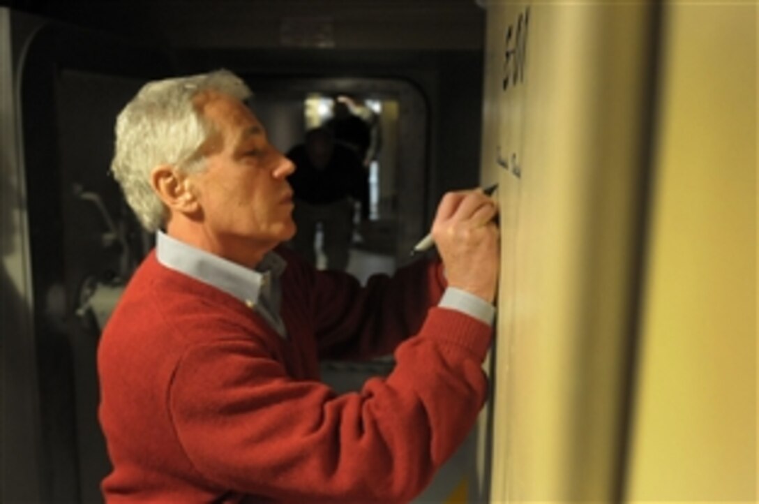 Defense Secretary Chuck Hagel autographs a bulkhead reserved for distinguished visitors as visits the E-01 Missile Alert Facility and Launch Control Center near Cheyenne, Wyo., Jan. 9, 2014.