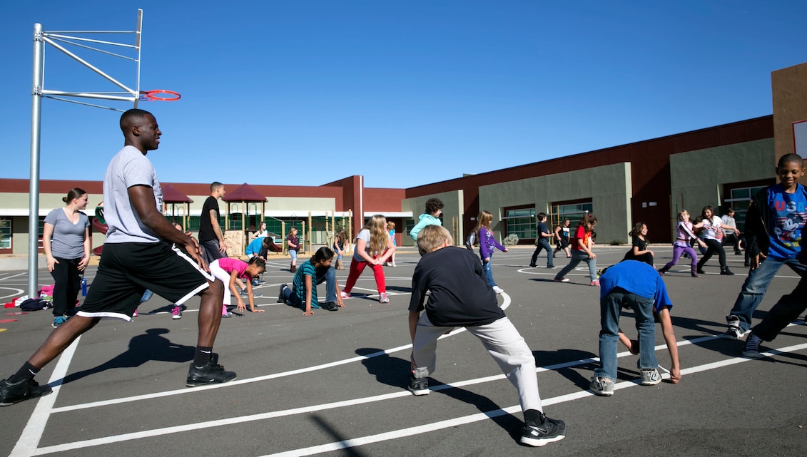 Lance Cpl. Delon David, small-arms repairer, Combat Logistics Company 13, leads elementary school students in stretches during physical education class at Joshua Tree Elementary School, Joshua Tree, Calif., Jan. 8. Five Marines with the company visited the school as part of the Adopt-a-School program. (Official Marine Corps Photo By Lance Cpl. Kasey Peacock/Released)