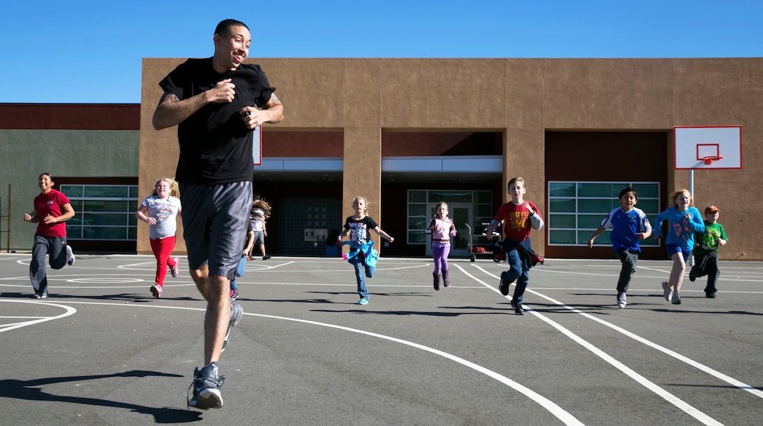 Cpl. Norberto Torres, automotive organizational mechanic, Combat Logistics Company 13, runs with elementary school students during a visit to Joshua Tree Elementary School, Joshua Tree, Calif., Jan. 8. Five Marines with the company visited the school as part of the Adopt-a-School program. (Official Marine Corps Photo By Lance Cpl. Kasey Peacock/Released)


