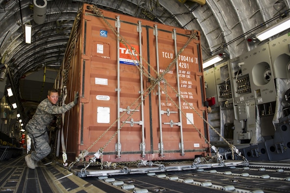 Tech. Sgt. James Schenck, 405th Logistics Readiness Squadron cargo and special handling noncommissioned officer in charge, pushes a container express box off a C-17A Globemaster III and onto a K-loader at an undisclosed location in Southwest Asia, Dec. 31, 2013. Schenck is deployed from Peterson Air Force Base, Colo., and is assigned to the 405th Air Expeditionary Group. (U.S. Air Force photo by Staff Sgt. Stephany Richards) 
