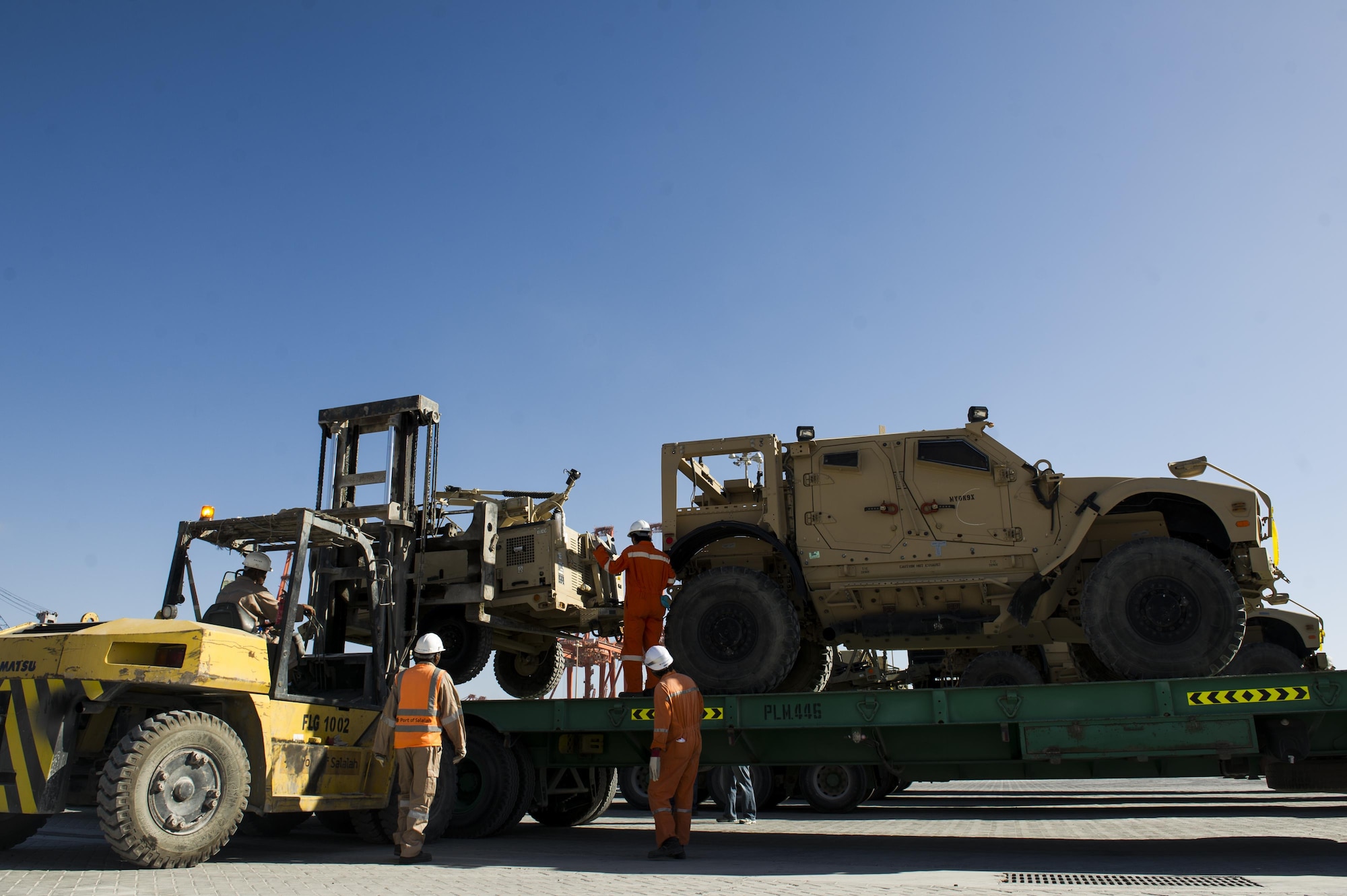 Contractors with the 405th Air Expeditionary Group unload a Mine Resistant Ambush-Protected vehicle from a flatbed trailer at the sea port at an undisclosed location in Southwest Asia, Dec. 31, 2013. The 405th AEG supports U.S. Central Command's Deployment and Distribution Operation Center, a strategically located air, land and sea logistics hub, playing a critical role in the U.S. departure from Afghanistan. (U.S. Air Force photo by Staff Sgt. Stephany Richards) 
