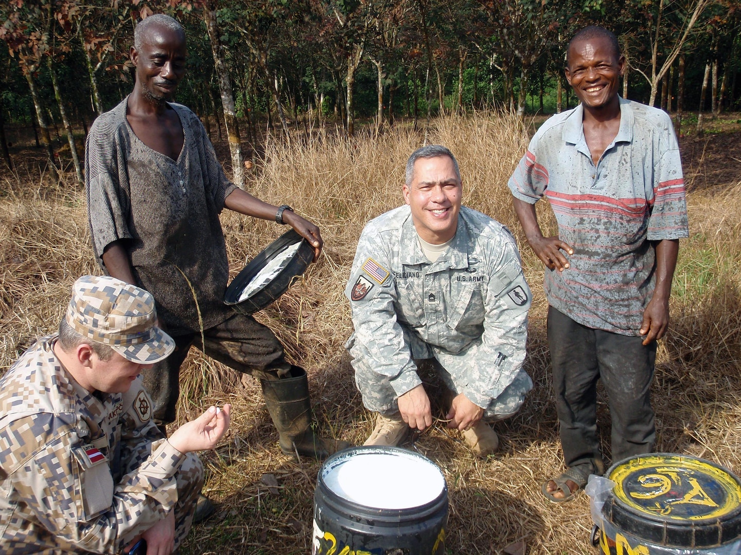 Michigan National Guard Master Sgt. Santos Feliciano and Latvian National Armed Force 1st Sgt. Martins Kupcs pose with workers from a rubber plantation in Liberia, Jan. 16, 2013. Michigan and Latvia are partners in the Department of State and DoD State Partnership Program and Liberia is Michigan's newest partner.