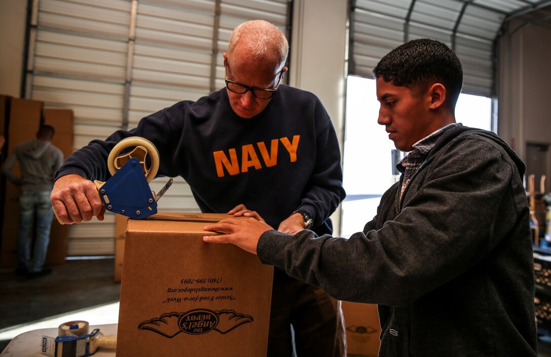 Lieutenant Cmdr. David Dinkins, left, chaplain, and Cpl. Richard Hernandez, data network specialist, both with the 15th Marine Expeditionary Unit, assemble a box during a volunteer event at The Angel's Depot in Vista, Calif., Jan. 10, 2014. More than 10 Marines and sailors with the 15th MEU volunteered for the event. (U.S. Marine Corps photo by Cpl. Emmanuel Ramos/Released)