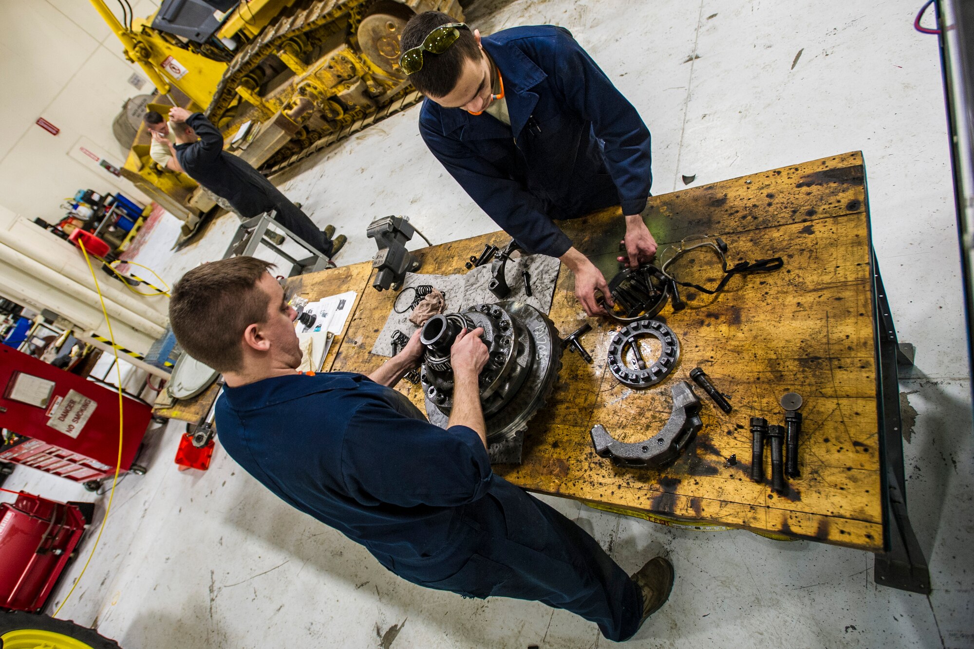 U.S. Air Force Senior Airman Anthony Tavares and Airman 1st Class Mitch Whitman, 354th Logistics Readiness Squadron vehicle maintenance flight, disassemble a differential from a flightline snow broom Jan. 9, 2014, Eielson Air Force Base, Alaska. Keeping the flightline cleared is a 24-hour job during the Alaskan winter. (U.S. Air Force photo by Senior Airman Joshua Turner/Released)